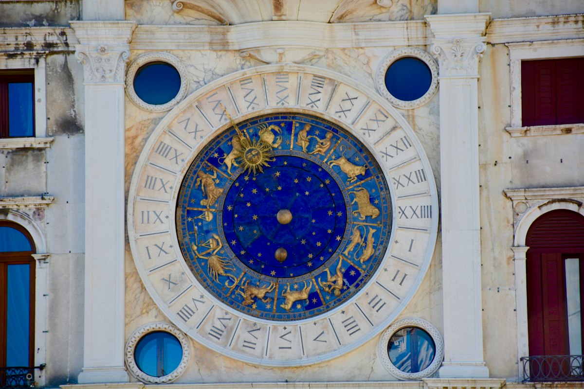 An ornate golden zodiac wheel on a deep blue starry dial